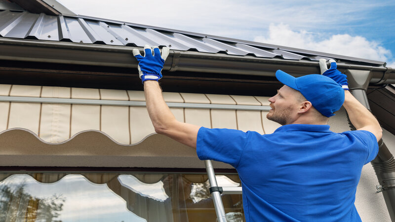 man installing house roof rain gutter system